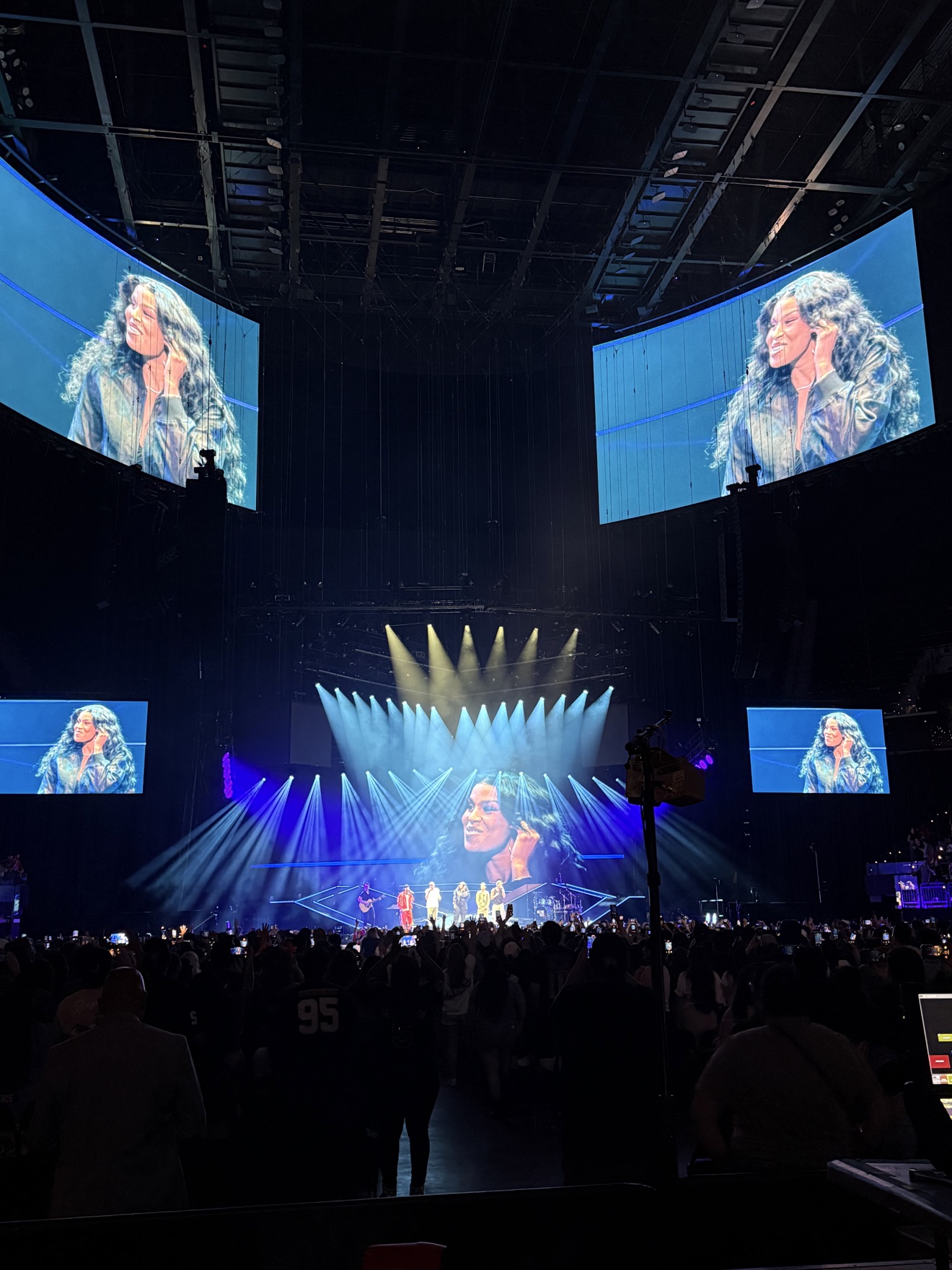 Concert arena filled with a crowd beneath dramatic spotlights